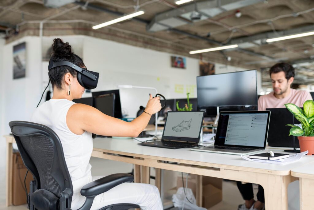 mujer sentada en la oficina utilizando gafas de realidad virutal delante del ordenador